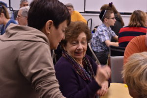 Seated resident speaking to a Temple Beth Am Congregant who is leaning into the conversation with interest.